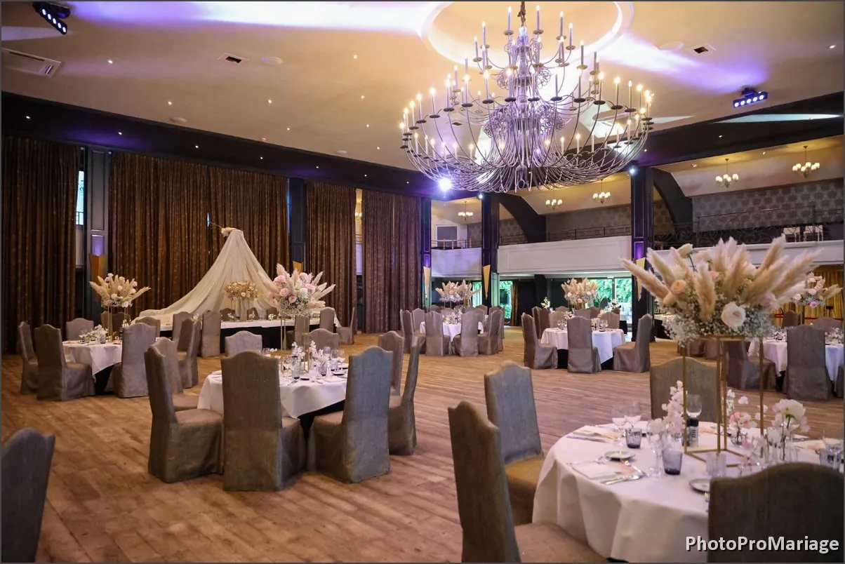 Salle de réception de mariage avec tables rondes, fleurs et grand lustre