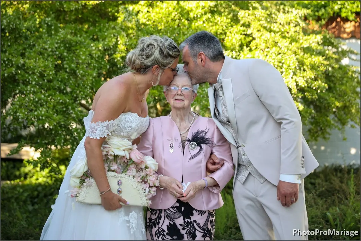 Les mariés enlacent une grand-mère, tous les trois en train de rire