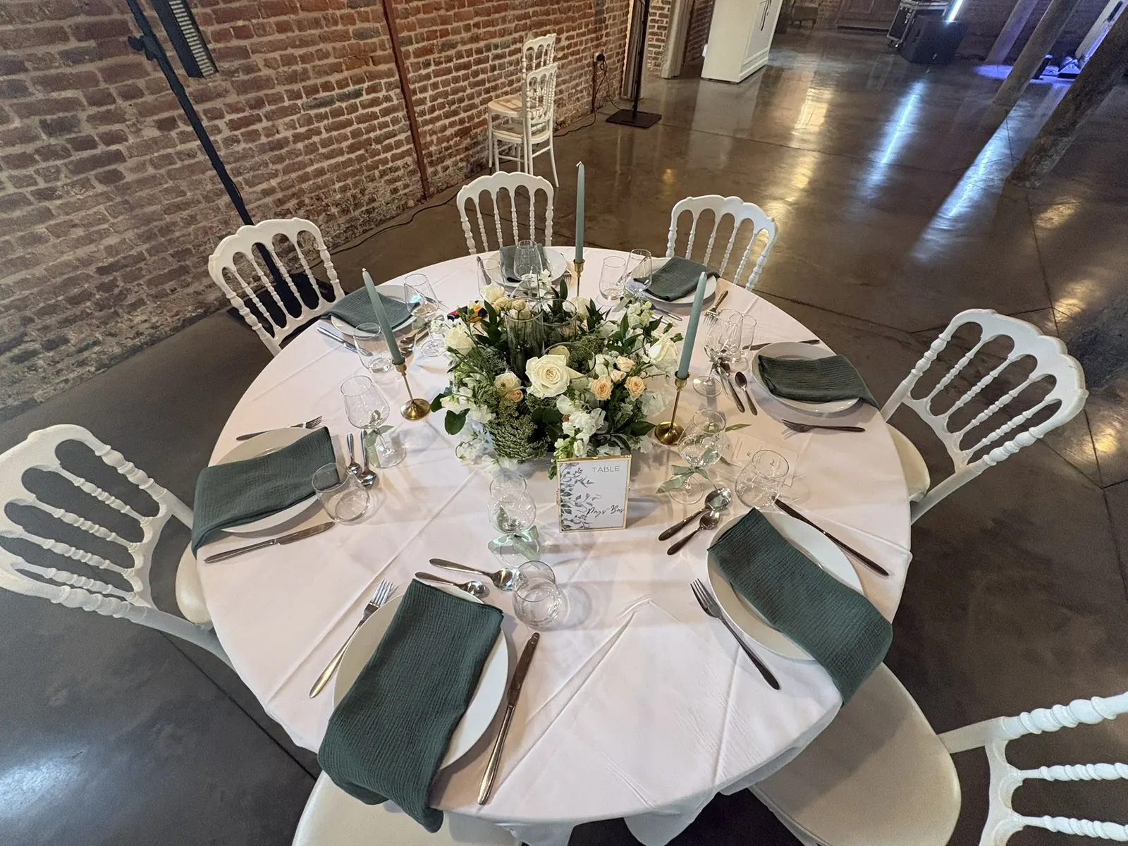 Table ronde de mariage aux tons blanc et vert sauge dans un ancien atelier
