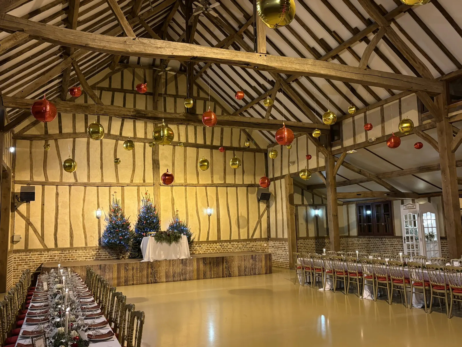 La grange d'Harmonie et Anthony, longues tables dressées sous les boules de Noël suspendues